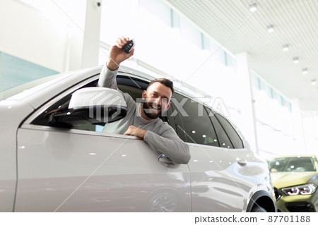 a man bought a car and joyfully shows the keys in a car dealership 87701188