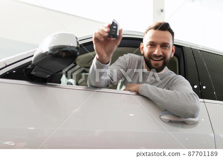 a satisfied customer looks out of the car with a key in his hands 87701189