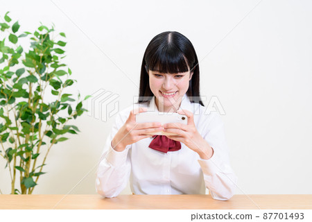 觀看通過將智能手機橫著拿來操作應用遊戲的高中女生的視頻 87701493