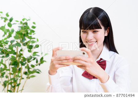 觀看通過將智能手機橫著拿來操作應用遊戲的高中女生的視頻 87701494