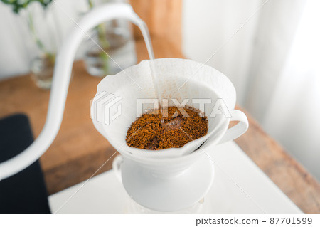 Drip coffee,Pouring a hot water over a drip coffee on the table Drip coffee,Pouring a hot water over a drip coffee on the table 87701599