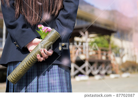 Student holding a diploma in front of school Up Bokeh in front of cherry blossoms 87702087
