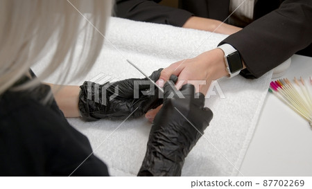 A close-up of a master doing a manicure to a young girl in a beauty salon. The concept of nails, manicure, beauty, fashion. 87702269