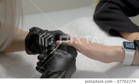 A close-up of a master doing a manicure to a young girl in a beauty salon. The concept of nails, manicure, beauty, fashion. 87702274