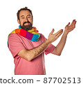 excited bearded man in the 40s, pointing to copy space with two hands outstretched on white background. casual wear and scarf lgtbq concept 87702513