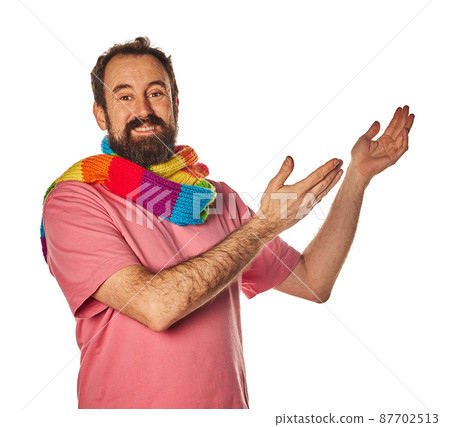 excited bearded man in the 40s, pointing to copy space with two hands outstretched on white background. casual wear and scarf lgtbq concept 87702513