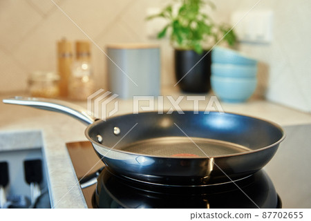 Frying pan on induction hob at kitchen Frying pan on induction hob at kitchen 87702655