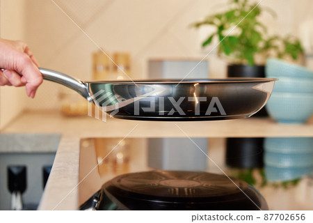 Woman use frying pan on induction stove 87702656
