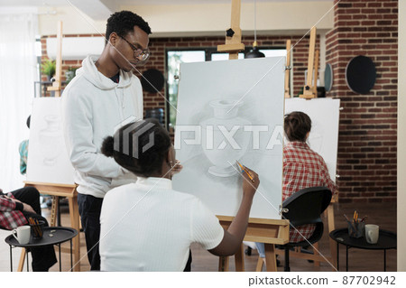 Painter teacher explaining illustration technique to student 87702942