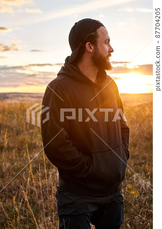 Relaxed guy in black wear having rest outdoors, in nature. Male after sport 87704205