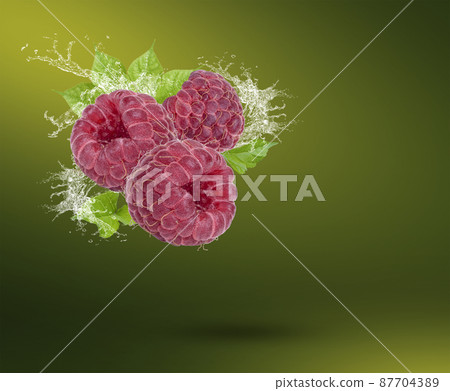 Water splash on fresh raspberry with leaves isolated on green background. 87704389
