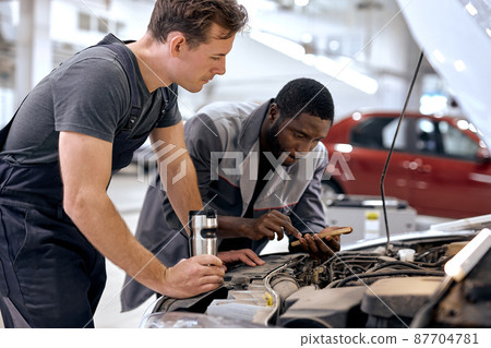 two men mechanic inspection checking bug in engine from application smartphone. 87704781