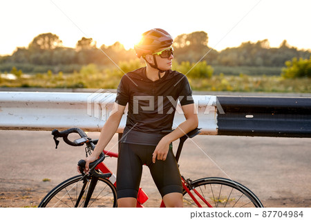 Professional sporty cyclist in black helmet, protective glasses and active wear have rest 87704984
