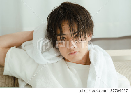 Young man drying wet hair with a towel 87704997