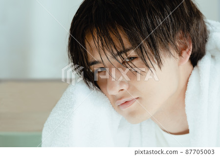 Young man drying wet hair with a towel Young man drying wet hair with a towel 87705003