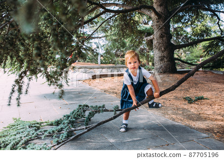 Little girl walks in the garden among beautiful evergreen southern plants 87705196