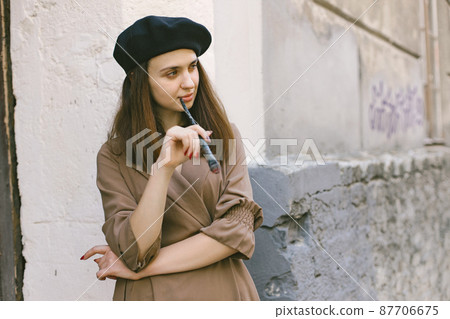 Girl in dress and black hat with painting brush in her hands Girl in dress and black hat with painting brush in her hands 87706675