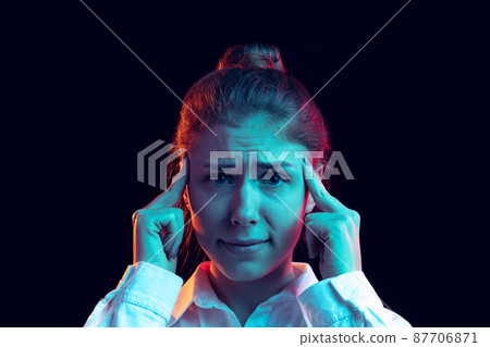 Half-length portrait of young pretty girl in white shirt isolated on dark background in blue neon light, filter. Concept of emotions, fashion, youth Half-length portrait of young pretty girl in white shirt isolated on dark background in blue neon light, filter. Concept of emotions, fashion, youth 87706871