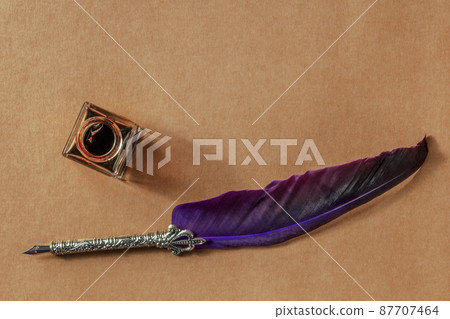 A quill pen with a vintage ink well, overhead flat lay shot on brown paper A quill pen with a vintage ink well, overhead flat lay shot on brown paper 87707464