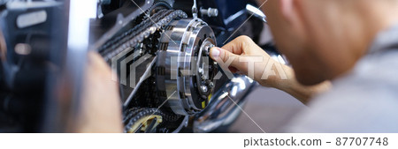 Mechanic repairs motorcycle engine in workshop closeup 87707748