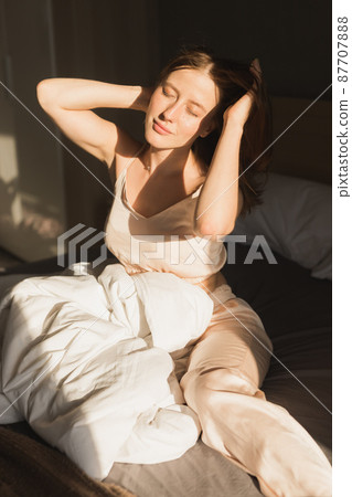 Girl is waking up in morning stretches in bed and sun shines from the window. Happy young woman greets new sunny day Girl is waking up in morning stretches in bed and sun shines from the window. Happy young woman greets new sunny day 87707888