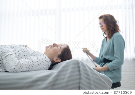 Caucasian woman crying while lying on the couch at a session with a psychologist. 87710509