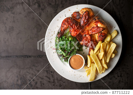 fried chicken tobacco with french fries and tomato sauce on a dark background. top view 87711222
