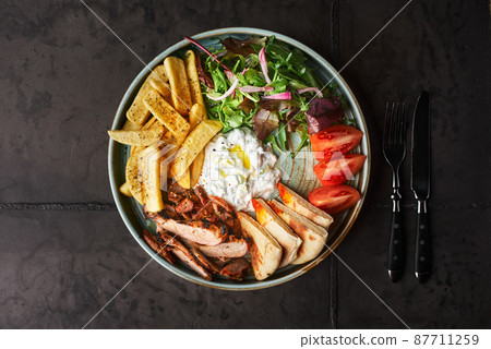 Greek Gyros with chicken or veal, with tzatziki on a dark background Greek Gyros with chicken or veal, with tzatziki on a dark background 87711259