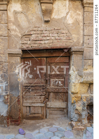 Broken wooden door on grunge stone bricks wall in abandoned street Broken wooden door on grunge stone bricks wall in abandoned street 87711264