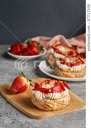 Choux pastries. Craquelin Choux biscuits. crispy cream puffs with cream filling and Strawberries Choux pastries. Craquelin Choux biscuits. crispy cream puffs with cream filling and Strawberries 87711508