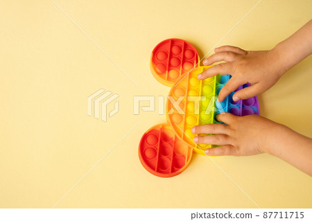 A child bursts the pimples of the popular popit toy. Useful toys for the development of fine motor skills of the fingers. Anti-stress toy. entertaining games for children and adults. simple dimple. A child bursts the pimples of the popular popit toy. Useful toys for the development of fine motor skills of the fingers. Anti-stress toy. entertaining games for children and adults. simple dimple. 87711715