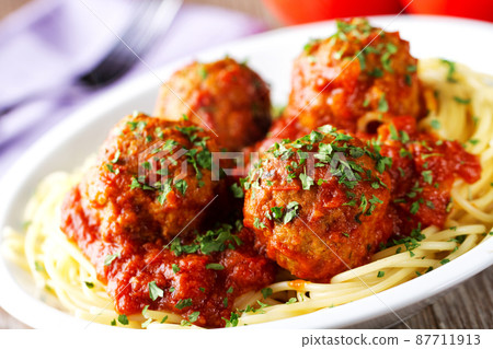 Spaghetti pasta with meatballs in tomato sauce and herbs on a white plate. Spaghetti pasta with meatballs in tomato sauce and herbs on a white plate. 87711913