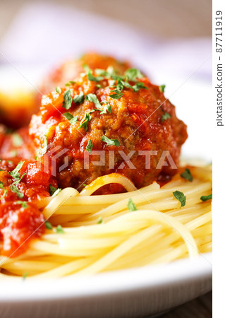 Spaghetti pasta with meatballs in tomato sauce and herbs on a white plate. Spaghetti pasta with meatballs in tomato sauce and herbs on a white plate. 87711919