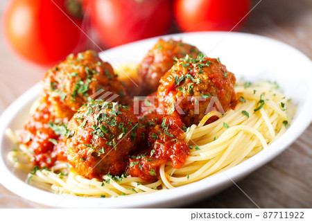 Spaghetti pasta with meatballs in tomato sauce and herbs on a white plate. 87711922