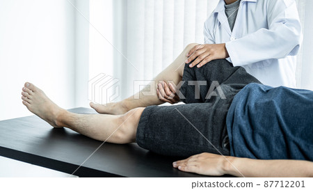 Female physiotherapist doing healing treatment and rehabilitation injured knee of patient by stretching 87712201