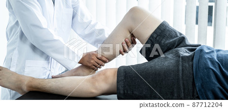 Female physiotherapist doing healing treatment and rehabilitation injured legs and ankle of patient by stretching 87712204
