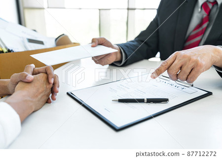 Close up of the hand employer focus the employee to write a letter of resignation and filing final remuneration, resign concept Close up of the hand employer focus the employee to write a letter of resignation and filing final remuneration, resign concept 87712272