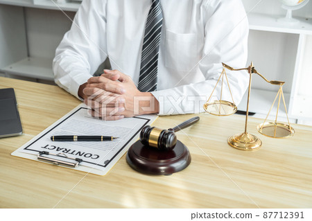 Male lawyer or jurist working with litigation contract paper documents of the estate lawsuit, Law books and wooden gavel on table in office Male lawyer or jurist working with litigation contract paper documents of the estate lawsuit, Law books and wooden gavel on table in office 87712391