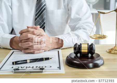 Male lawyer or jurist working with litigation contract paper documents of the estate lawsuit, Law books and wooden gavel on table in office Male lawyer or jurist working with litigation contract paper documents of the estate lawsuit, Law books and wooden gavel on table in office 87712393