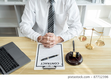 Male lawyer or jurist working with litigation contract paper documents of the estate lawsuit, Law books and wooden gavel on table in office 87712396