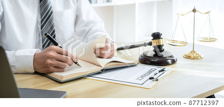 Male lawyer or jurist working with litigation contract paper documents of the estate lawsuit, Law books and wooden gavel on table in office 87712397