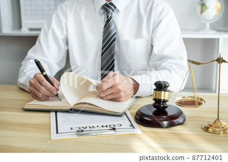 Male lawyer or jurist working with litigation contract paper documents of the estate lawsuit, Law books and wooden gavel on table in office 87712401