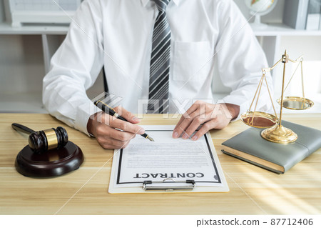 Male lawyer or jurist working with litigation contract paper documents of the estate lawsuit, Law books and wooden gavel on table in office 87712406
