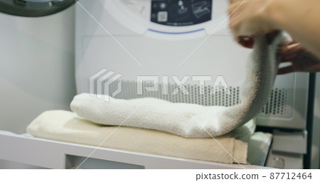 Close up of young woman folds towels after washing in laundry room. 87712464