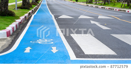 Blue bicycle lane on road with white bicycle icon and arrow. Empty Bicycle way for bike. Blue bicycle lane on road with white bicycle icon and arrow. Empty Bicycle way for bike. 87712579
