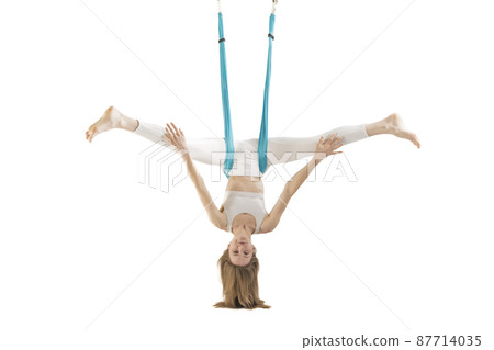 Woman doing antigravity yoga with yoga hammock isolated on white background. Girl hangs upside down. 87714035