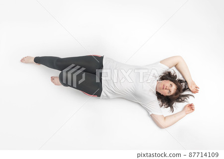 Portrait of plus size woman in sportswear lies on white background. Model with curvy figure. Top view 87714109