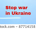 Stop the war in Ukraine. Inscription on a background of blue sky in red letters. Trace of an airplane in the sky. Russia's invasion of Ukraine. 87714158