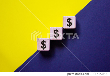 Wood cubes with dollar sign stacking as step stair on paper blue and yellow background, copy space. Business concept success process. Wood cubes with dollar sign stacking as step stair on paper blue and yellow background, copy space. Business concept success process. 87715036