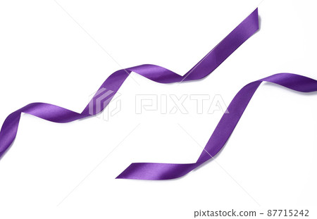 swirling purple silk ribbon on white background, gift wrapping decor. Top view swirling purple silk ribbon on white background, gift wrapping decor. Top view 87715242